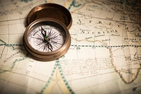 Antique compass lying on old style map Stock Photos