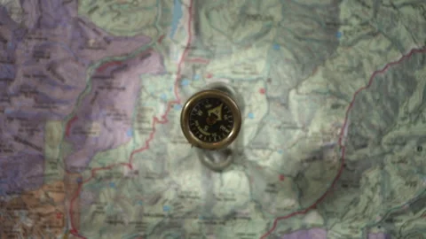 An antique compass zeroing in on true north with a map background Stock Footage 220960829