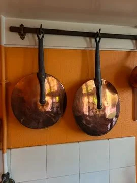 Antique Copper Pans Hanging on Rustic French Kitchen Wall Fotos de archivo