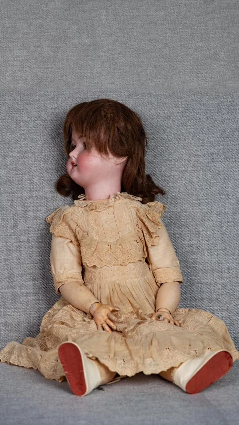 Antique doll isolated on a gray couch with looping spinning head Vidéo 330378193