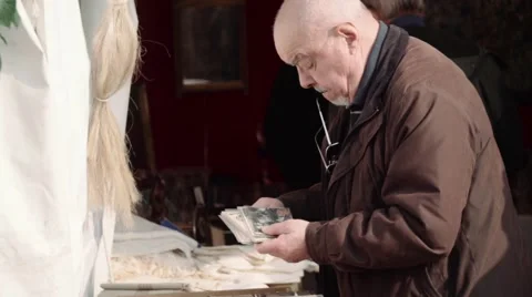 Antique Fair- Old Man looking at old photos Stock Footage 61410826