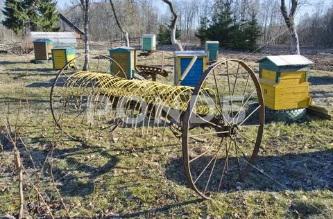 Antique horse-drawn rake and beehive in farm garden Stock Photos