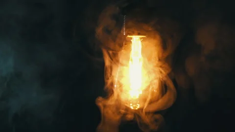 Antique Light Bulb Flashes Orange in Fog on Black Background Stock Footage 263906432