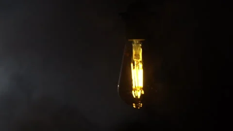 Antique Light Bulb Flashes Orange in Fog on Black Background Video stock 264339967