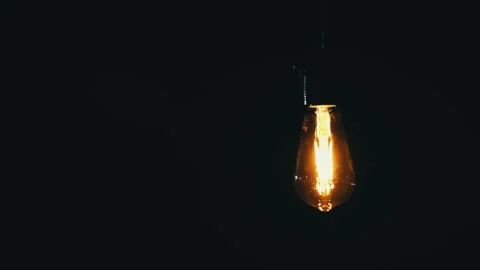 Antique Light Bulb Lights Up in Orange on a Black Background Stock Footage 263827962