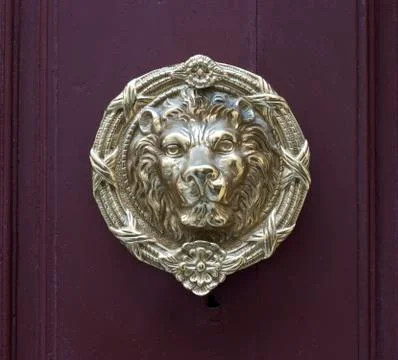 An antique lion head pull handle knob on a vintage wooden red door Photos
