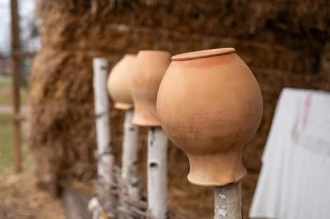 Antique rustic clay jugs placed neck down on a wooden fence, against the back Stock Photos