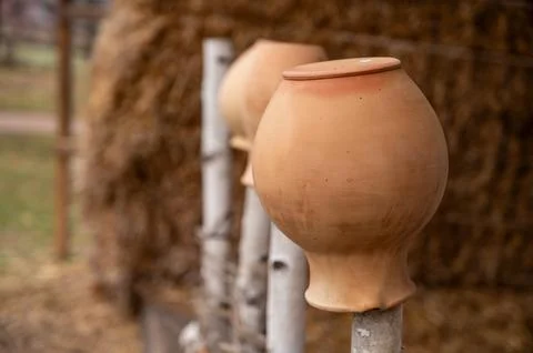 Antique rustic clay jugs placed neck down on a wooden fence, against the back Stock Photos