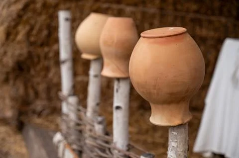 Antique rustic clay jugs placed neck down on a wooden fence, against the back Stock Photos