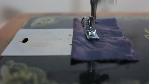 An antique sewing machine in motion, pushing thread through blue cotton cloth Stock Footage 345001420