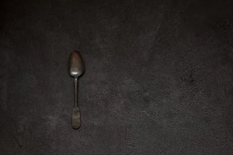 Antique silver spoon on a black concrete style. Stock Photos