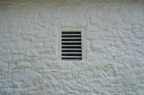 Antique slatted window in whitewashed colonial stone barn. Foto stock