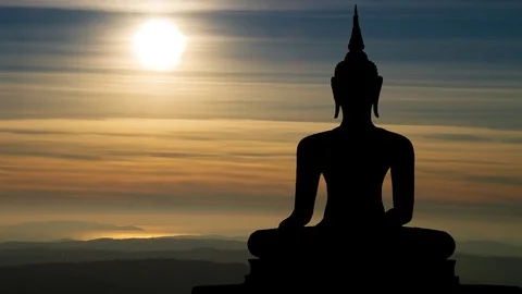 Antique Statue of Buddah at Sunset in Time Lapse with Sun and Orange Clouds Stock Footage 101512330