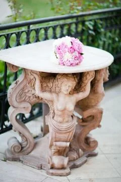 Antique statue supporting a table with wedding bouquet. Simple purple-white c Stock Photos