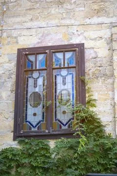 Antique stone wall featuring an intricate stained glass window. The medieval Stock Photos