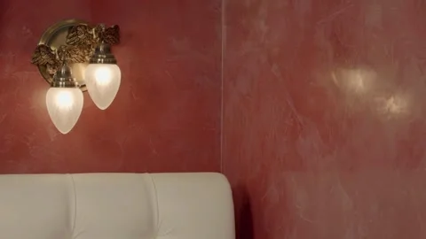 An antique-style night light with bronze birds and two lamps on a red shiny wall Stock Footage 297749079