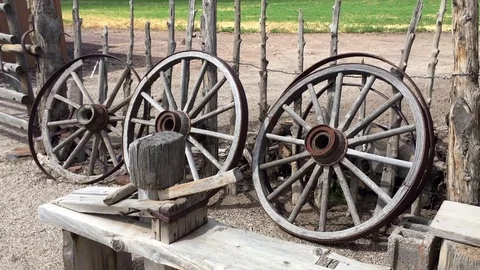 Antique wagon wheels lined up against fence HD Stock-Footage 80165861