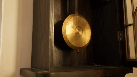 Antique wall clock with a pendulum. Man's hand starts pendulum, closeup Stock Footage 71951108