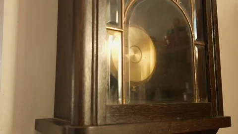 Antique wall clock with a pendulum. Man's hand stopping pendulum,closeup Stock Footage 71951126