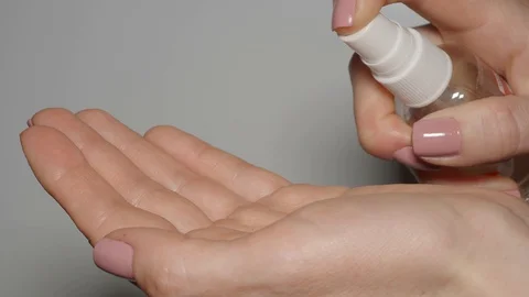 Antiseptic spray being applied on woman's hands. Close up Stock Footage 128446296