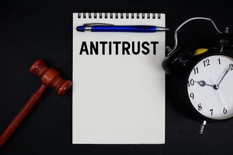 Antitrust text written on notepad with gavel and alarm clock on black backg.. Stock Photos