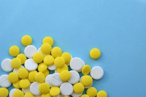 Antiviral white and yellow tablets for treatment on a blue background. Flat l Stock Photos