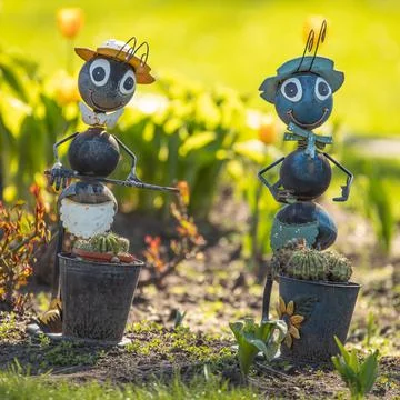 Ants, garden toys. A pair of large decorative metal ornaments on a flower bed Stock Photos