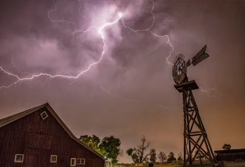 Anvil crawling lightning illuminates an old barn during a thunderstorm Stock Photos
