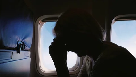 Anxiety and experience in flight. Silhouette of a young woman in an airplane Stock Footage