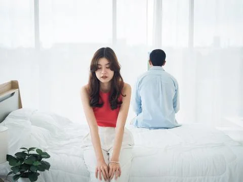 The anxiety of Asian couple lovers on the bed. Sad young woman and man sittin Stock Photos
