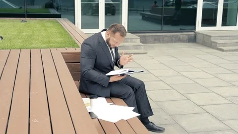Anxious business man looking for something in a notebook sitting outdoors Stock Footage 110749255