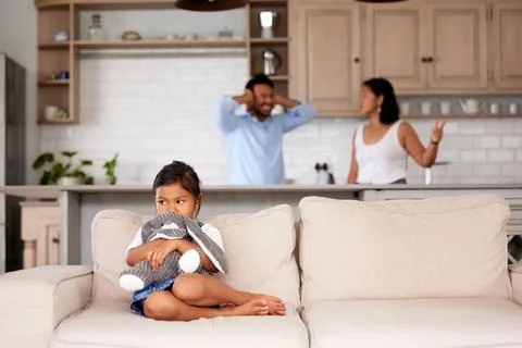 Anxious girl comforting herself by holding her teddy while her parents argue in Stock Photos