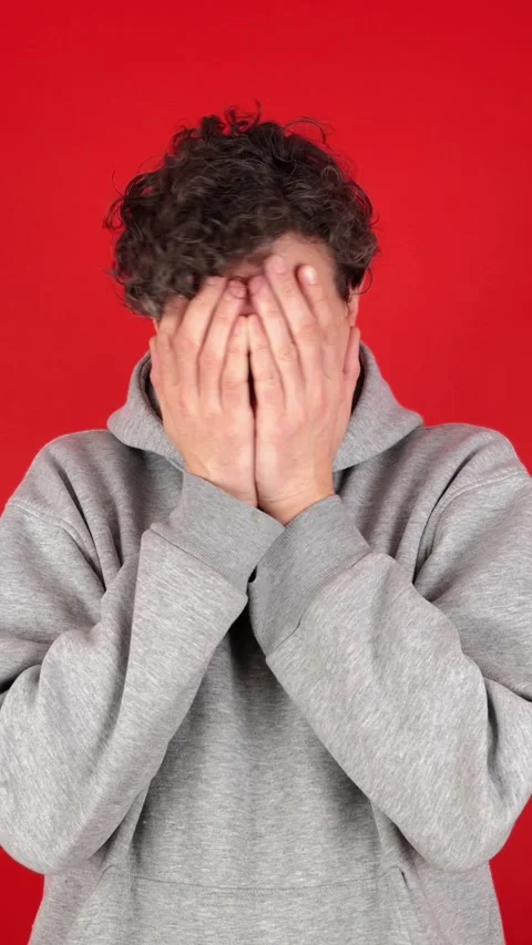Anxious man covers face hands, looks through fingers, shakes head Видео 304761720