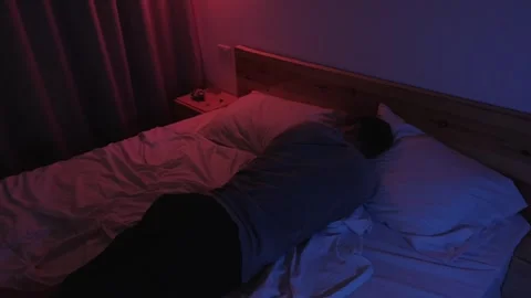 Anxious man curled up alone in bed, withdrawing into a fetal position and Stock-Footage 347300558