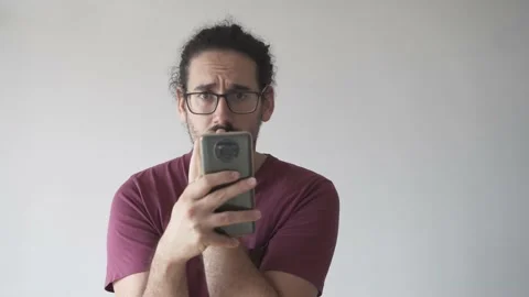 Anxious man with smartphone biting his nails and looking at camera Stock Footage 161551879