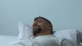 Anxious man waking up frightened in bed night, nightmare, troubled sleep, stress HD Footage