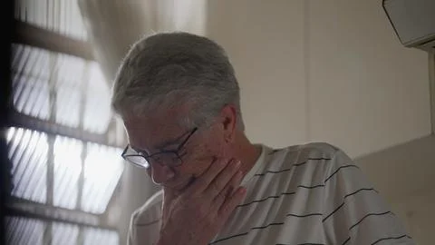 Anxious Older Man standing by window feeling worry. Regretful gray hair per.. Stock Photos