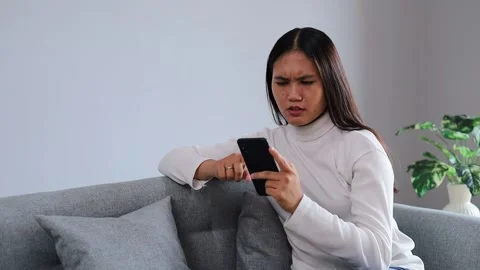 Anxious woman browsing smartphone message sitting home couch, reading Stock Footage 328640237