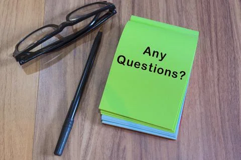 Any question text on green notepad with glasses and pen on a desk Stock Photos