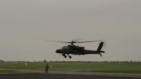 Apache helicopter flying low in a field full of helicopters Stock Footage 113344967