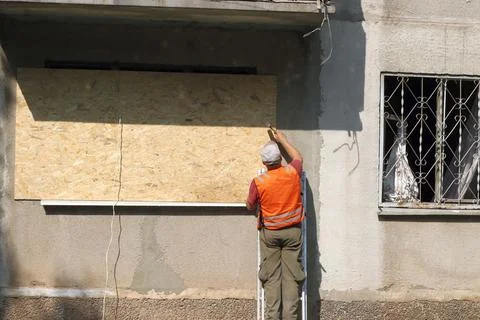 An apartment building with the aftermath of a rocket attack and temporary w.. Stock Photos
