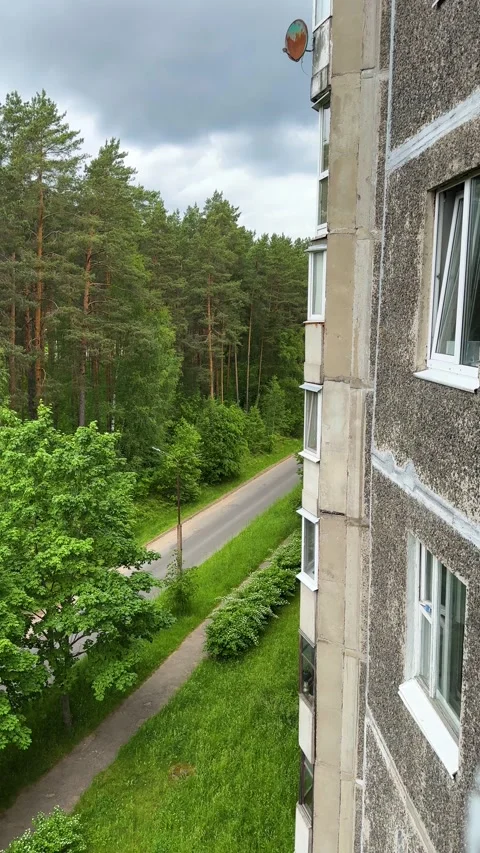 Apartment building near green forest and road under cloudy sky Stock Footage 336542553
