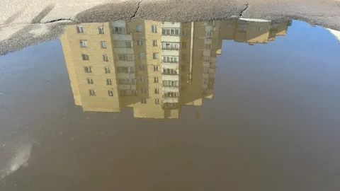 Apartment building reflection in street puddle, upside down mirror image Stock Footage 340148989