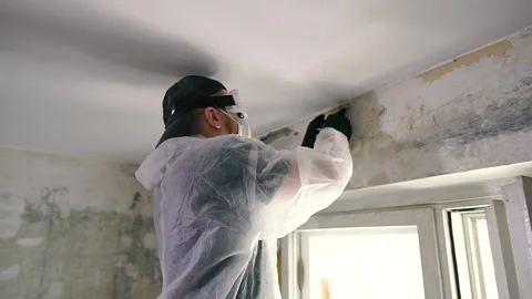Apartment renovation. The builder cleans the old wallpaper for the new one. Stock Footage 151585019