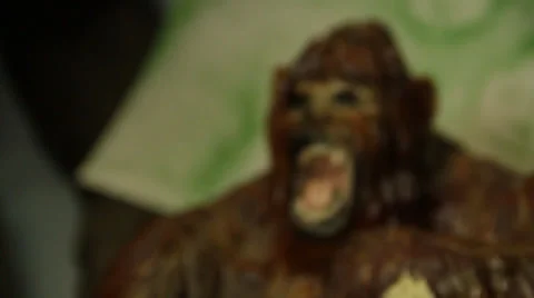 Ape doll looks wood sasquatch big foot bigfoot monster teeth in front of camera Stock Footage