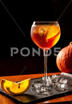 Aperol Spritz cocktail with pumpkin and orange slices and ice on black tray o Stock Photos