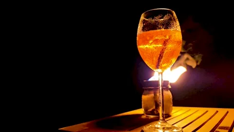 Aperol spritz glowing in firelight at night, with visible bubbles and flick.. Stock Footage 340281285
