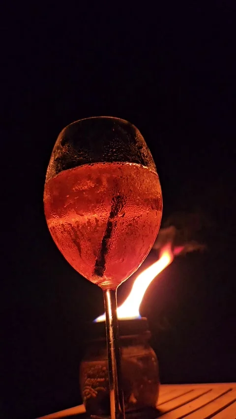 Aperol spritz glowing in firelight at night, with visible bubbles and flick.. Stock Footage 340281290
