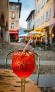Aperol Spritz served on a table with a charming Italian historic town in the Photos