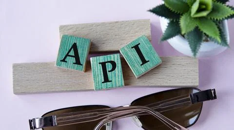 API - acronym on wooden cubes on the background of glasses and cactus Foto stock